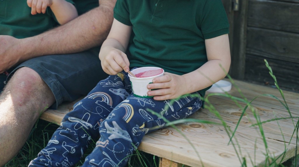 Kind mit einem Becher auf der Holzbank am Hansl Hof